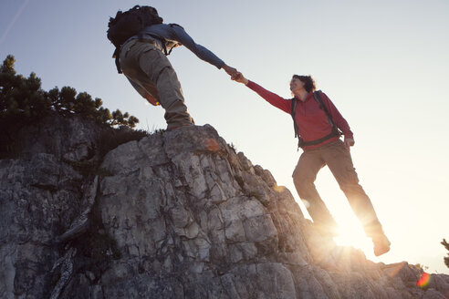 Austria, Tyrol, Unterberghorn, man helping woman on hiking trip - RBF002930