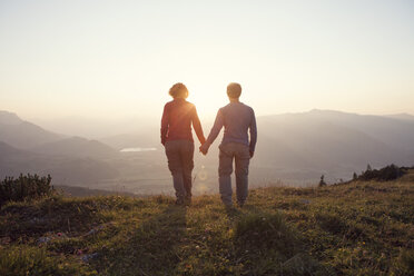 Austria, Tyrol, couple walking hand in hand at Unterberghorn at sunset - RBF002939