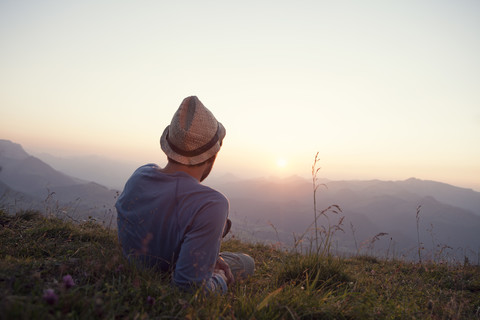 Austria, Tyrol, Unterberghorn, man resting on alpine meadow at sunset stock photo