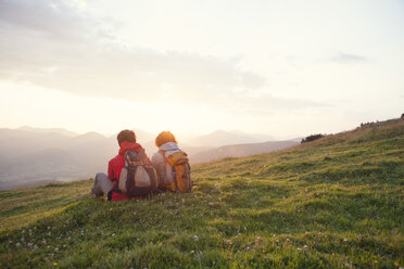 Österreich, Tirol, Unterberghorn, zwei Wanderer rasten in alpiner Landschaft bei Sonnenaufgang - RBF002957