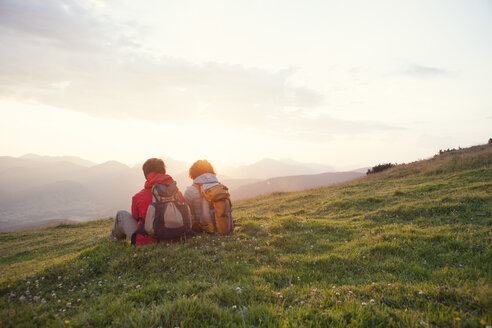 Österreich, Tirol, Unterberghorn, zwei Wanderer rasten in alpiner Landschaft bei Sonnenaufgang - RBF002957