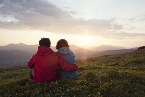 Österreich, Tirol, Unterberghorn, zwei Wanderer rasten in alpiner Landschaft bei Sonnenaufgang - RBF002958