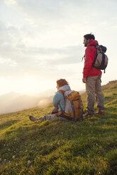 Österreich, Tirol, Unterberghorn, zwei Wanderer rasten in alpiner Landschaft bei Sonnenaufgang - RBF002966