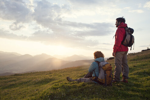 Österreich, Tirol, Unterberghorn, zwei Wanderer rasten in alpiner Landschaft bei Sonnenaufgang - RBF002967
