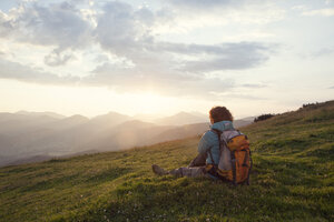 Österreich, Tirol, Unterberghorn, Wanderer rastet in alpiner Landschaft bei Sonnenaufgang - RBF002968