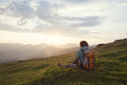 Austria, Tyrol, Unterberghorn, hiker resting in alpine landscape at sunrise - RBF002968