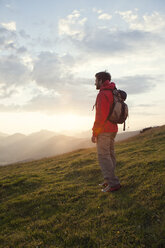 Austria, Tyrol, Unterberghorn, hiker standing in alpine landscape at sunrise - RBF002969