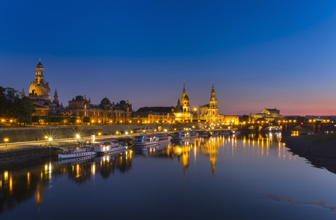 Deutschland, Sachsen, Dresden, Beleuchtete historische Altstadt mit Elbe im Vordergrund bei Nacht, lizenzfreies Stockfoto
