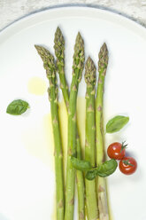 Grüner Spargel, Olivenöl, Tomaten und Basilikum auf einem Teller - ASF005644