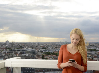 Germany, Berlin, young woman looking at her smartphone - BFRF001400