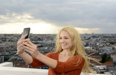 Germany, Berlin, young woman taking a selfie with her smartphone - BFRF001401