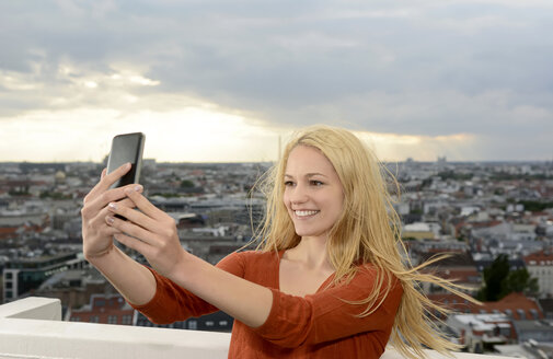 Deutschland, Berlin, junge Frau macht ein Selfie mit ihrem Smartphone - BFRF001401