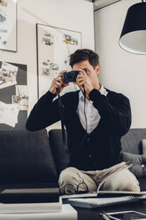 Young man sitting on sofa taking a picture - CHAF000930