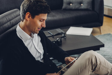 Young man in living room using digital tablet - CHAF000934