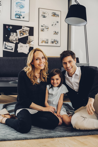 Glückliche Familie mit Tochter auf dem Boden sitzend im Wohnzimmer, lizenzfreies Stockfoto