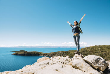 Bolivia, La Paz Department, Happy woman with raised arms on top of Isla del sol on Lake Titicaca - GEMF000294