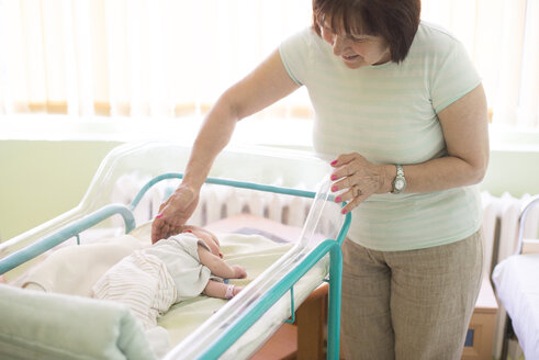 Ältere Frau beobachtet ihre neugeborene Enkelin in einem Krankenhaus - DEGF000476