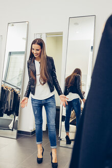 Lächelnde junge Frau präsentiert neue Kleidung in einer Boutique - CHAF001330