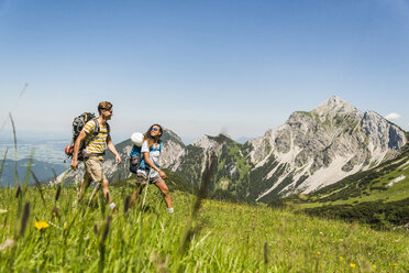 Österreich, Tirol, Tannheimer Tal, junges Paar wandert auf Almwiese - UUF005048