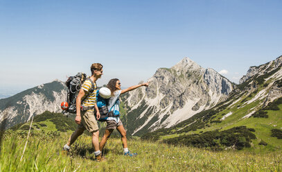 Österreich, Tirol, Tannheimer Tal, junges Paar wandert auf Almwiese - UUF005049