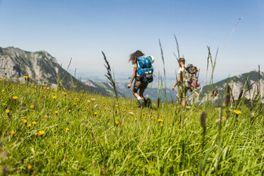 Österreich, Tirol, Tannheimer Tal, junges Paar wandert auf Almwiese - UUF005051