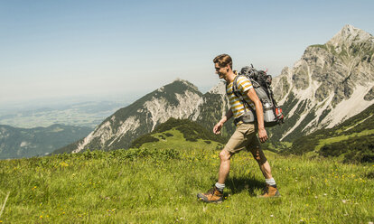 Österreich, Tirol, Tannheimer Tal, junger Mann wandert auf Almwiese - UUF005053