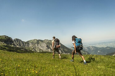 Österreich, Tirol, Tannheimer Tal, junges Paar wandert auf Almwiese - UUF005054