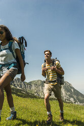 Austria, Tyrol, Tannheimer Tal, young couple hiking on alpine meadow - UUF005055