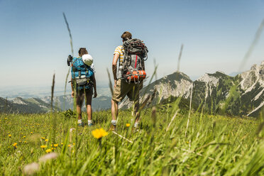 Österreich, Tirol, Tannheimer Tal, junges Paar steht auf einer Almwiese und betrachtet die Aussicht - UUF005057