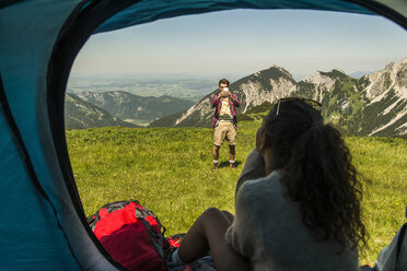 Österreich, Tirol, Tannheimer Tal, junger Mann fotografiert Frau im Zelt - UUF005060