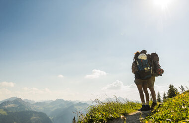 Austria, Tyrol, Tannheimer Tal, young couple standing on mountain trail looking at view - UUF005081