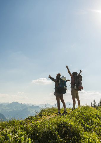 Österreich, Tirol, Tannheimer Tal, jubelndes junges Paar auf Bergpfad stehend mit Blick auf die Aussicht, lizenzfreies Stockfoto