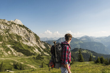 Österreich, Tirol, Tannheimer Tal, junger Mann wandert auf Almwiese - UUF005088