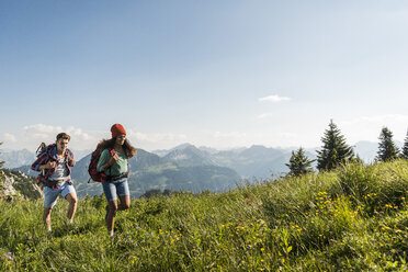 Österreich, Tirol, Tannheimer Tal, junges Paar wandert auf Almwiese - UUF005089