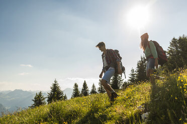 Österreich, Tirol, Tannheimer Tal, junges Paar wandert auf Almwiese - UUF005092