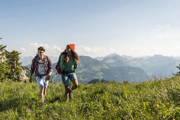 Österreich, Tirol, Tannheimer Tal, junges Paar wandert auf Almwiese - UUF005093