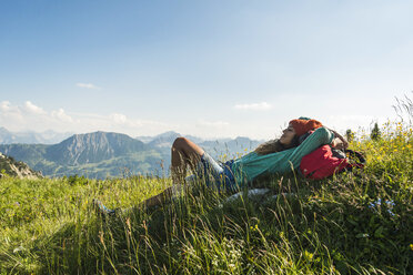 Austria, Tyrol, Tannheimer Tal, young woman lying on alpine meadow - UUF005100