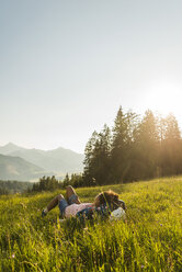 Österreich, Tirol, Tannheimer Tal, junge Frau auf Almwiese liegend - UUF005115