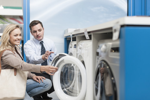 Shop assistant explaining washing machine to customer stock photo