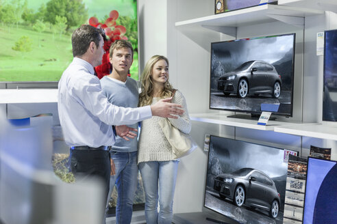 Verkäufer zeigt einem jungen Paar Flachbildfernseher - ZEF007346