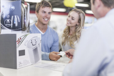 Young couple at counter in shop paying for purchase - ZEF007353