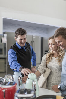 Verkäuferin im Gespräch mit jungem Paar beim Einkaufen von Küchengeräten - ZEF007359