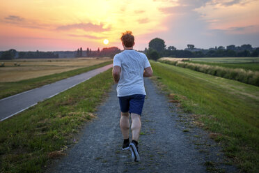 Rear view of man jogging at sunset - PUF000390