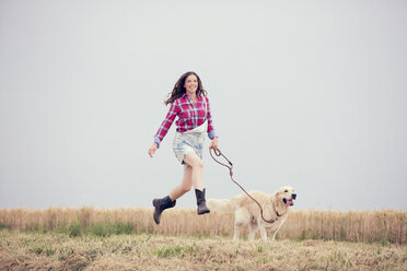 Junge Frau und ihr Golden Retriever auf einem Feld - MAEF010835