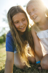 Two sisters crouching side by side on a meadow - MGOF000356