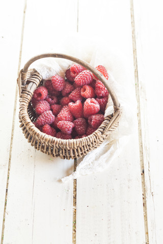 Weidenkorb mit Raspelbeeren auf weißem Holz, lizenzfreies Stockfoto