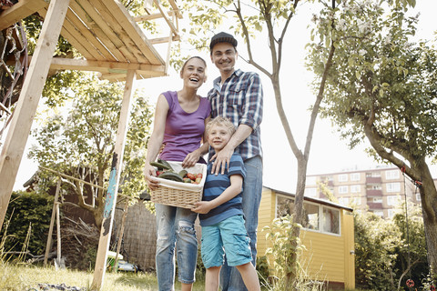 Stolze Familie präsentiert Korb mit frischem Gemüse im Garten, lizenzfreies Stockfoto