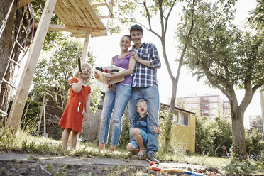 Glückliche Familie hält Korb mit frischem Gemüse im Garten - RHF000994