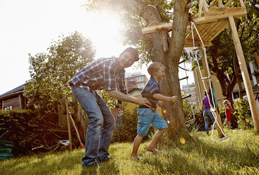 Glückliche Familie beim Spielen im Garten - RHF001013