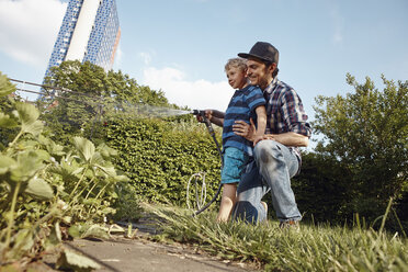 Vater und Sohn gießen Pflanzen im Garten - RHF001036